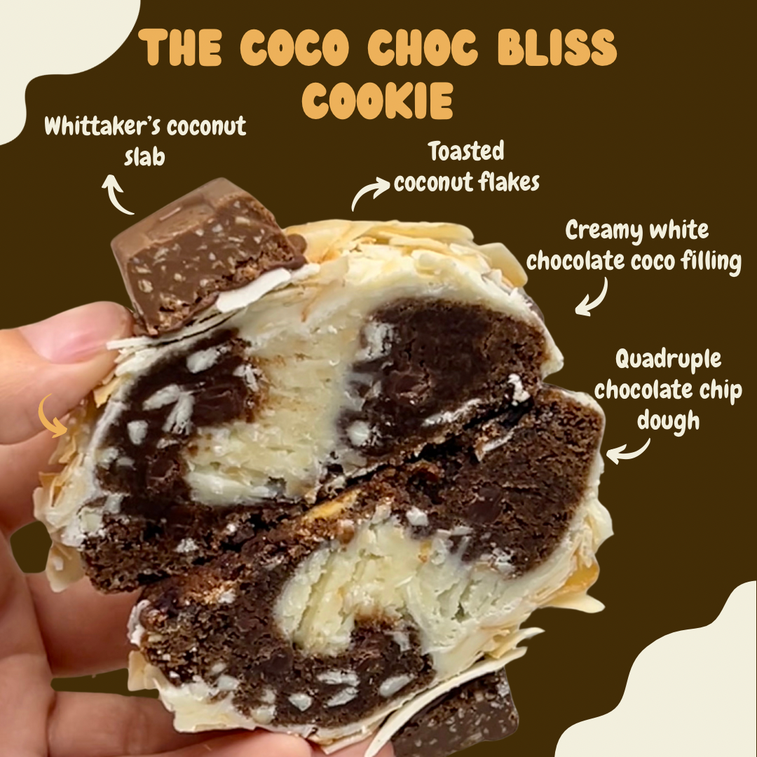 The coco-choc Cookie topped with toasted coconut flakes and a slab of Whittaker’s coconut chocolate, showing the creamy white chocolate and coconut filling inside