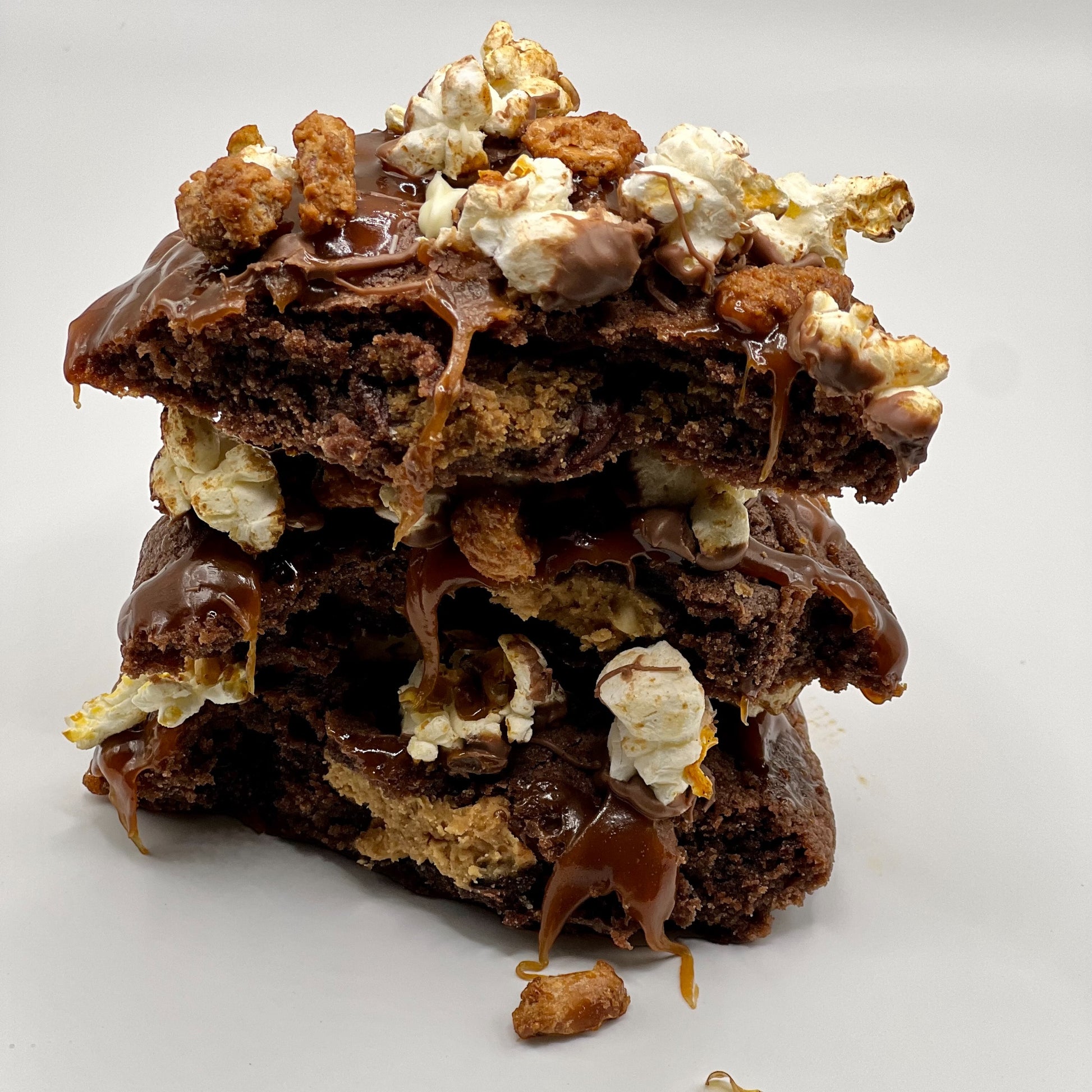 The Cinema Crunch Chocolate Cookie from The Dough Corner – featuring a blend of dark, milk, and white chocolate chips with a creamy peanut butter center, topped with caramel bits and candied peanuts. Perfect for a decadent dessert or movie night treat.